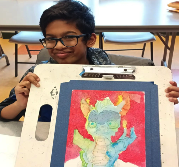 Happy boy holding up dragon painting